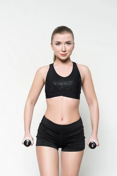 Mujer joven en ropa deportiva levantando pesas aisladas en blanco - foto de stock