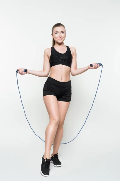 Athletic girl jumping on skipping rope isolated on white — Stock Photo