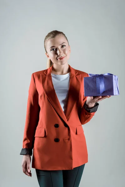 Mujer sonriente sosteniendo caja de regalo aislada en gris - foto de stock