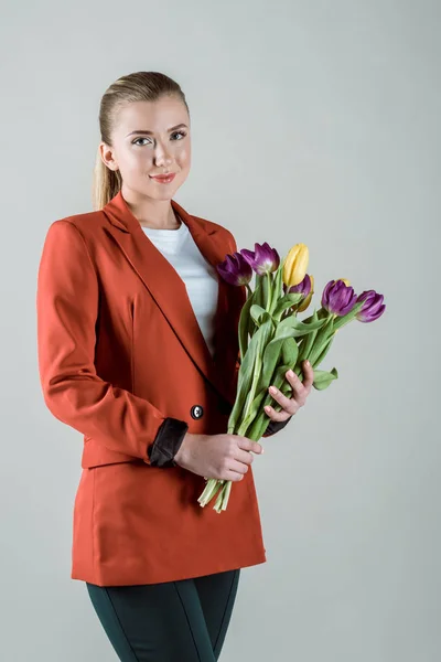 Junges Mädchen hält Tulpen isoliert auf grau — Stockfoto