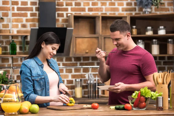 Felice giovane uomo e donne incinte che cucinano insieme in cucina — Foto stock