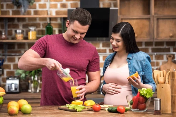 Heureux jeune couple enceinte serrant jus frais ensemble — Photo de stock