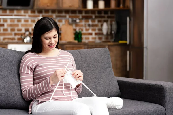 Beautiful smiling young pregnant woman knitting at home — Stock Photo