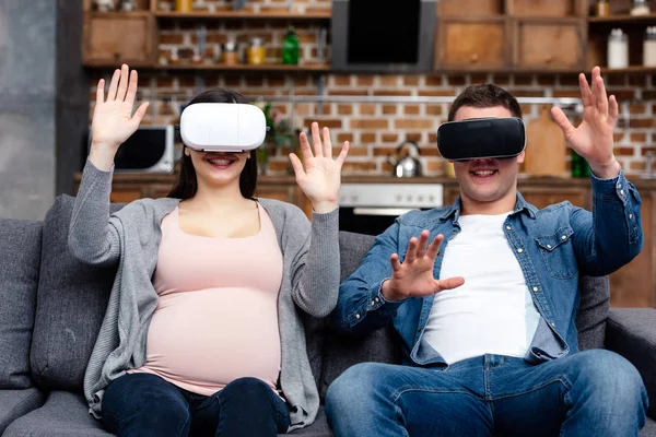 Smiling young pregnant couple using virtual reality headsets together at home — Stock Photo