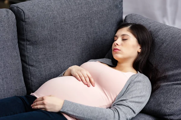 Молодая беременная женщина спит на диване дома — стоковое фото