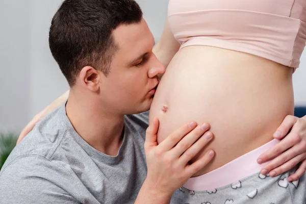 Cropped shot of man kissing tummy of pregnant woman — Stock Photo