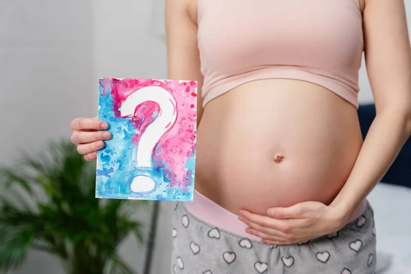 Tiro recortado de grávida segurando cartão com ponto de interrogação — Fotografia de Stock