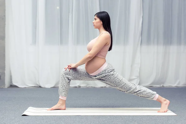 Vista laterale della giovane donna incinta che pratica yoga a casa — Foto stock