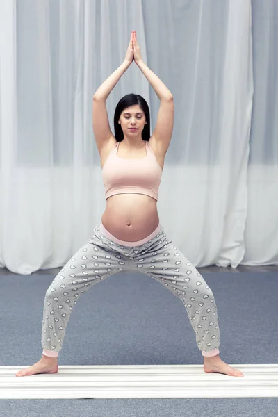 Jeune femme enceinte pratiquant le yoga à la maison — Photo de stock