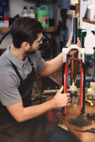 Junge Reparaturkraft im Vorfeld arbeitet mit Fahrrad in Werkstatt — Stockfoto