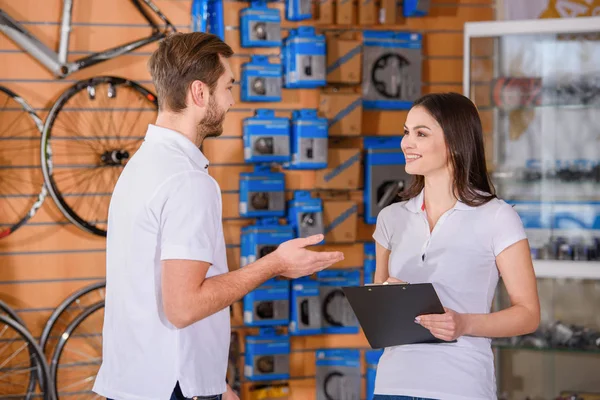 Lächelnde junge Manager, die sich bei der gemeinsamen Arbeit im Fahrradladen anschauen — Stockfoto