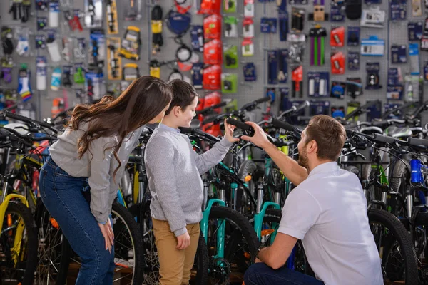 Gerente ajudando a escolher bicicleta para mãe feliz e filho na loja de bicicletas — Fotografia de Stock