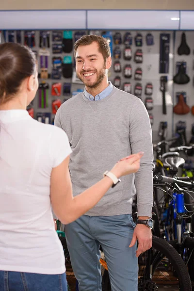 Manager and smiling byer talking and looking at each other in bicycle shop — Stock Photo