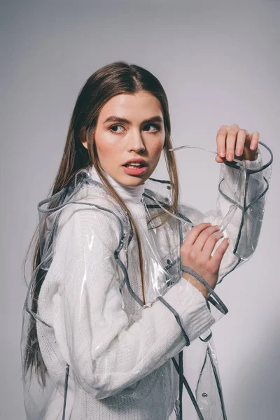 Fashionable pensive woman in trendy raincoat with eyeglasses looking away on grey background — Stock Photo