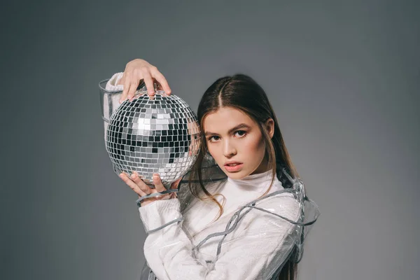 Retrato de mujer joven de moda con bola disco en las manos aisladas en gris - foto de stock