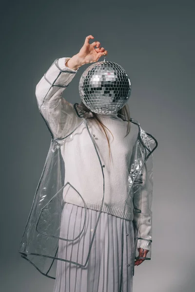 Oscurecido vista de la mujer con estilo cubriendo la cara con bola disco aislado en gris - foto de stock