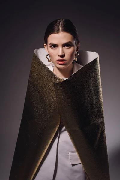 Portrait of fashionable woman in golden wrapping paper posing on dark backdrop — Stock Photo