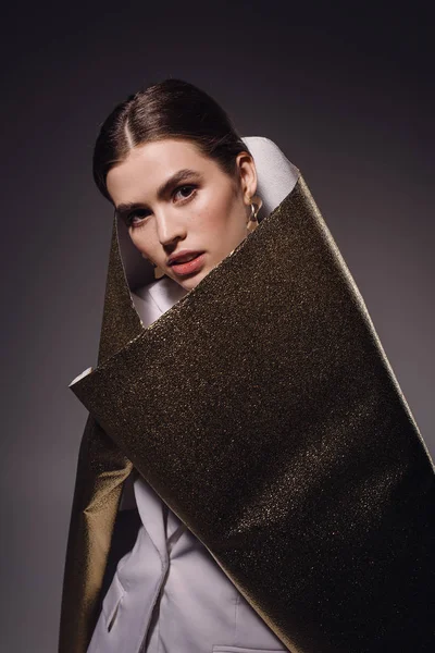 Portrait of fashionable woman in golden wrapping paper posing on dark backdrop — Stock Photo