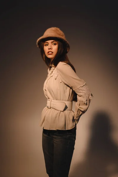 Portrait de belle femme en vêtements à la mode et chapeau posant sur fond sombre — Photo de stock