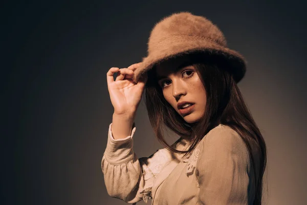 Retrato de mujer de moda en sombrero mirando hacia otro lado sobre fondo oscuro - foto de stock