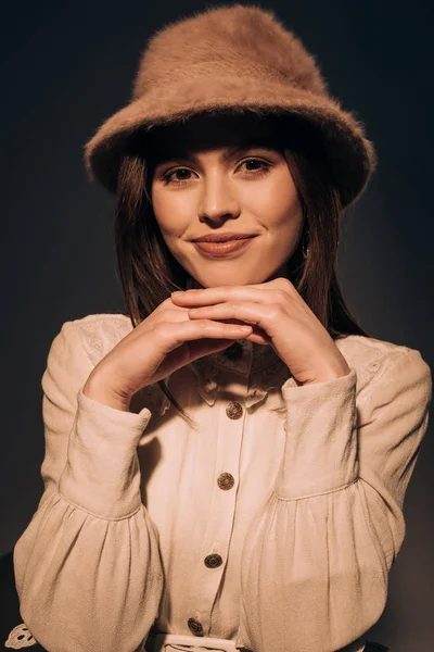 Retrato de hermosa mujer sonriente en sombrero de moda mirando a la cámara aislada en negro - foto de stock