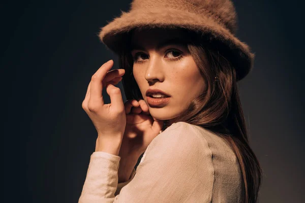 Porträt einer schönen jungen Frau mit stylischem Hut, die isoliert auf schwarz in die Kamera blickt — Stockfoto