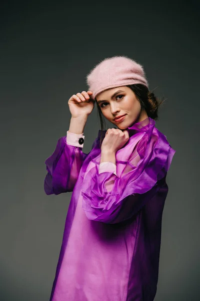 Portrait de femme à la mode en robe violette et chapeau regardant la caméra sur fond noir — Photo de stock