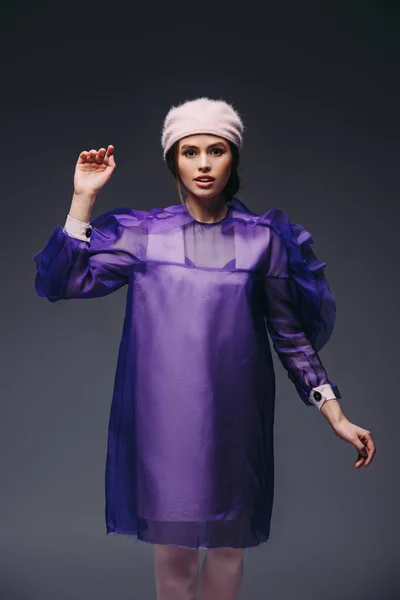 Портрет стильной женщины в фиолетовом платье и шляпе, позирующей на черном фоне — стоковое фото