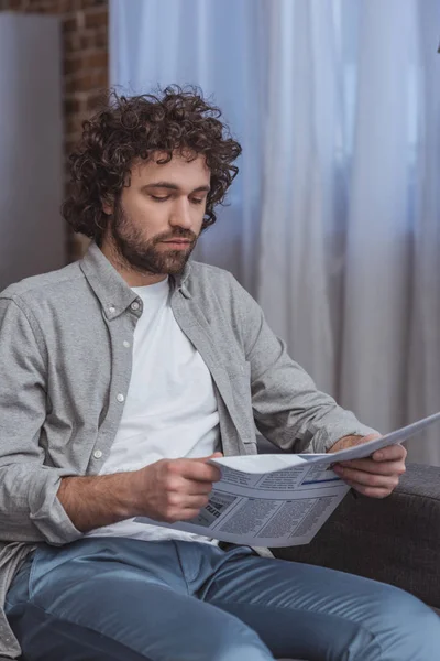 Hombre guapo leyendo periódico de negocios en la sala de estar - foto de stock