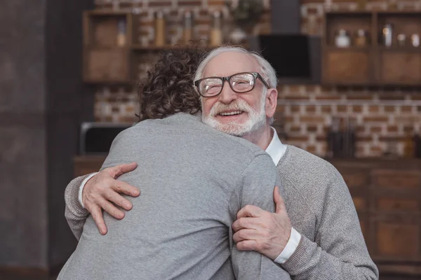 Счастливый взрослый сын и старший отец обнимаются дома — стоковое фото
