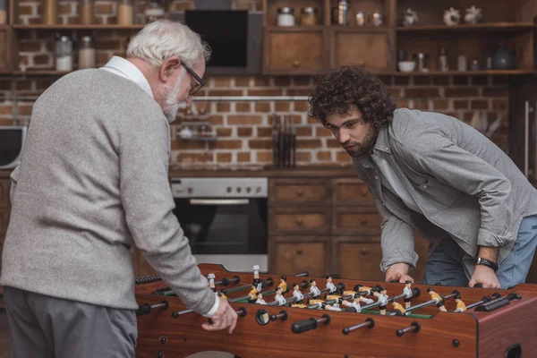 Erwachsener Sohn und älterer Vater spielen zu Hause Tischkicker — Stockfoto