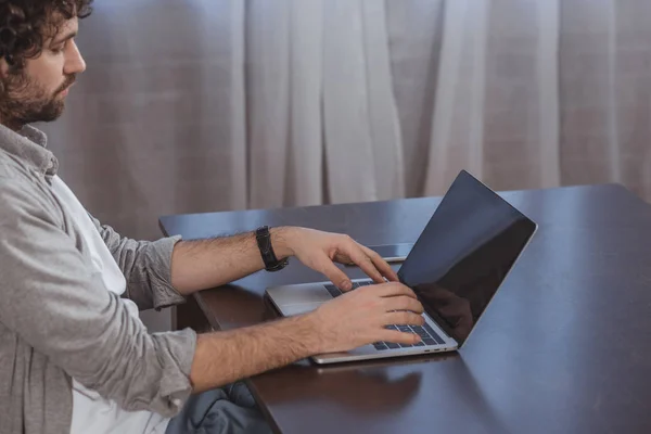 Vista lateral de homem bonito usando laptop em casa — Fotografia de Stock