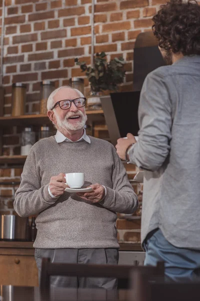 Heureux père aîné et fils adulte parlant avec café dans la cuisine — Photo de stock