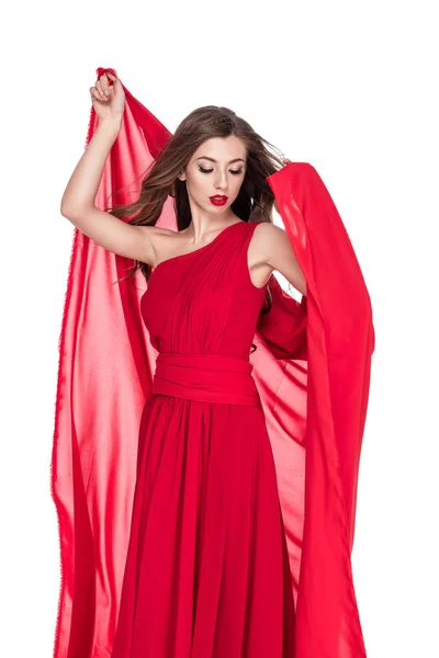 Приваблива жінка позує в червоній сукні з шифоновою завісою, ізольована на білому — стокове фото