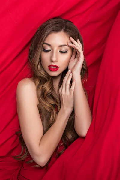 Attractive glamorous woman posing on red — Stock Photo