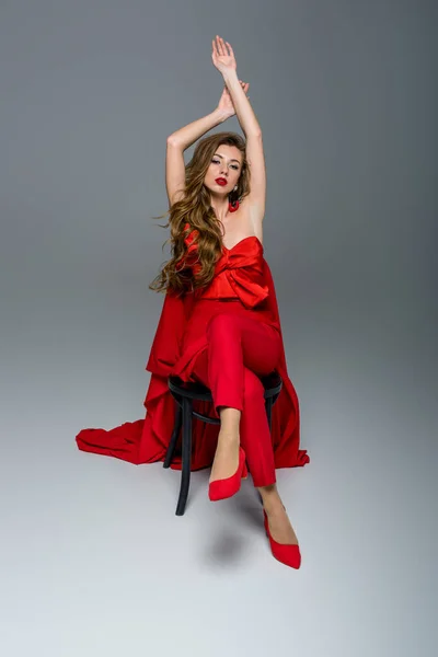 Seductive woman posing in red clothes, on grey — Stock Photo