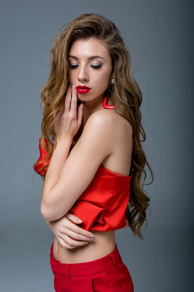 Bela mulher com cabelos longos em roupas vermelhas, isolado em cinza — Fotografia de Stock