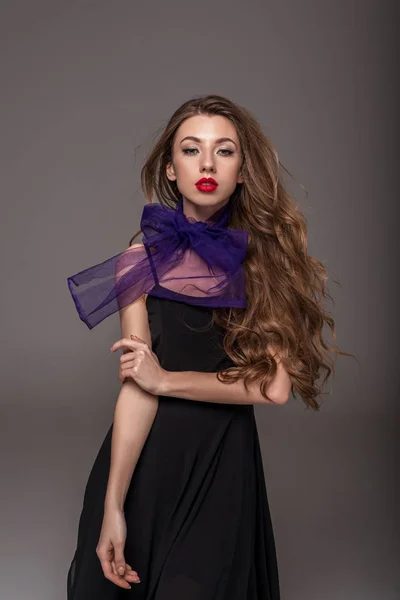 Schönes Mädchen mit langen Haaren posiert in lila Schal, isoliert auf grau — Stockfoto