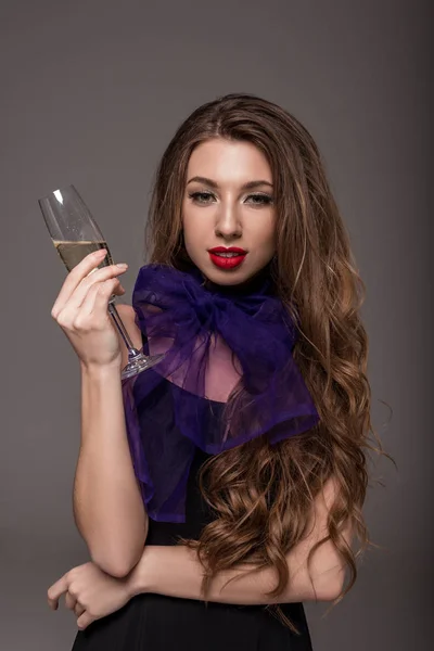 Hermosa chica en bufanda púrpura posando con copa de champán, aislado en gris - foto de stock
