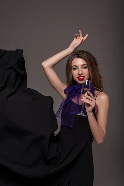 Atractiva mujer posando con copa de champán para sesión de moda, aislado en gris - foto de stock