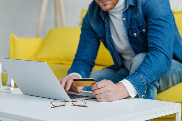 Человек делает онлайн оплату с помощью кредитной карты и ноутбука — стоковое фото