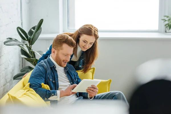 Woman looking at tablet screen in male hands — Stock Photo