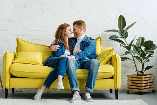 Pelirroja mujer y hombre abrazando en sofá — Stock Photo