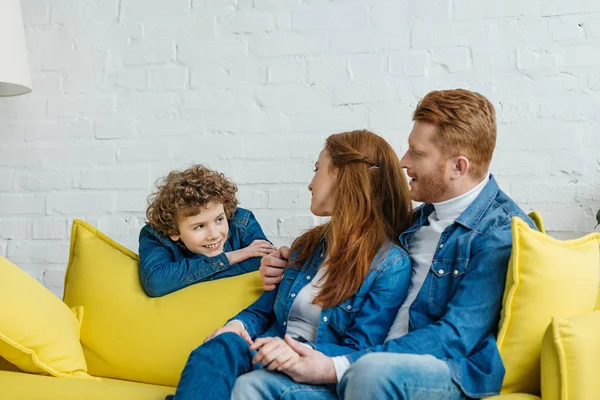 Eltern sitzen auf Sofa und schauen lächelnden Sohn an — Stockfoto