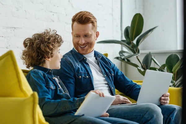 Sorrindo pai com filho usando tablet e laptop — Fotografia de Stock