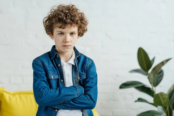 Serious child standing with arms folded — Stock Photo