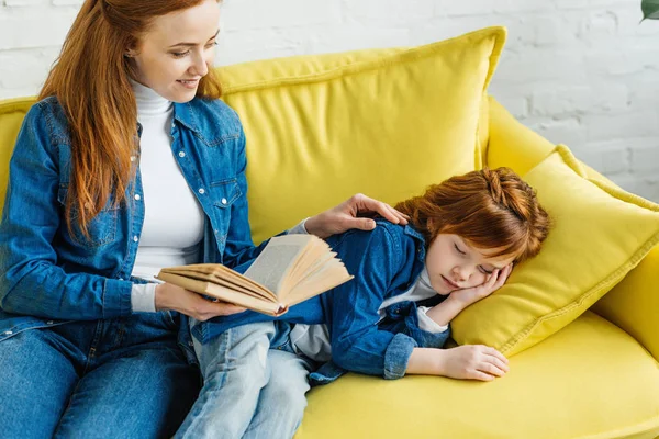 Schläfriges kleines Kind hört Mutter beim Lesen von Buch zu — Stockfoto