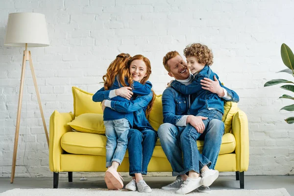 Enfants heureux et parents câlins sur le canapé — Photo de stock