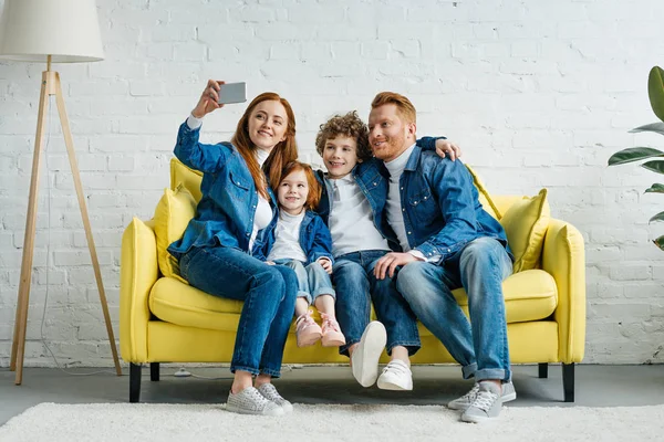 Щаслива сім'я приймає селфі, сидячи на дивані — стокове фото