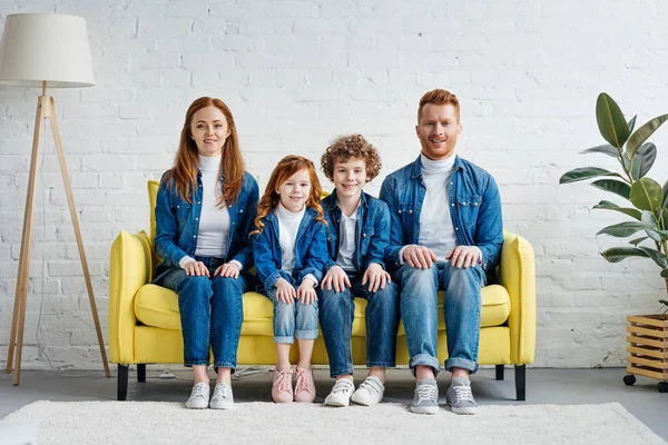 Famille souriante avec des enfants assis sur le canapé dans la chambre — Photo de stock